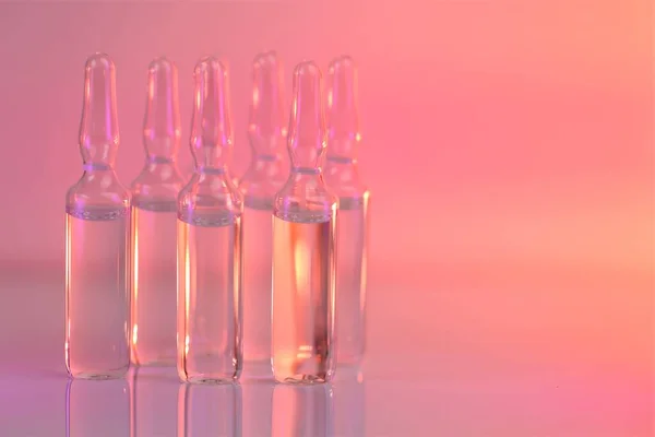 Biorevitalisierungsbehandlung, Mesotherapie-Lösung. Lösung für die Injektion. Biotechnologie und Wissenschaft. Medizin und Pharmazie. Transparente Äpfel in rosa Licht. Impfung und Medizin. — Stockfoto