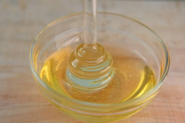 ¿Cariño? Miel líquida en frasco de vidrio con dipper.Palillo de vidrio para miel en una taza de vidrio sobre una mesa de madera. Miel fresca ecológica —  Fotos de Stock