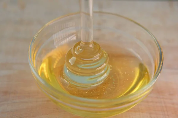 Honey. Liquid honey in glass jar with dipper.Glass stick for honey in a glass cup on a wooden table. Organic Fresh honey — Stock Photo, Image