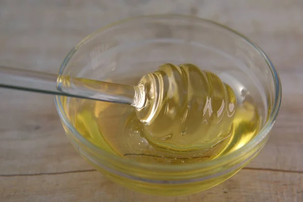 ¿Cariño? Miel líquida en frasco de vidrio con dipper.Palillo de vidrio para miel en una taza de vidrio sobre una mesa de madera. Miel ecológica —  Fotos de Stock
