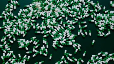 İlaç çerçevesi. Yeşil kapsüllü el ve yeşil tıbbi kapsüller. Tıp ve homeopati konsepti. Alternatif tıp yeşil arka planda homeopatik bitkisel yeşil kapsüller..