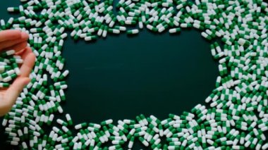 Haplar. Eller yeşil zemine tıbbi kapsüller döker. Yeşil arka planda homeopatik bitkisel yeşil kapsüller. Tıp ve homeopati konsepti. Alternatif tıp. yeşil haplar