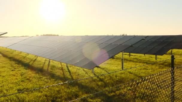 Zonne-energie boerderij achter het hek in het veld bij zonsondergang .pv panelen.Zonnepanelen. Alternatieve energiebronnen.Natuurlijke energie.Milieuvriendelijke natuurlijke energiebron — Stockvideo