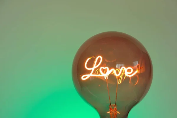 Heerlijk. Lampje met de inscriptie liefde op een smaragdgroene achtergrond. Valentijnsdag. — Stockfoto