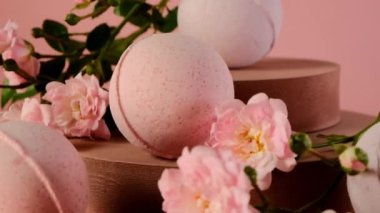 Çiçek Banyo Bombaları. Organik vejetaryen kozmetik. Açık pembe arka planda gül özlü banyo bombaları. Pembe banyo bombaları. Gül özlü kozmetik ürünleri.