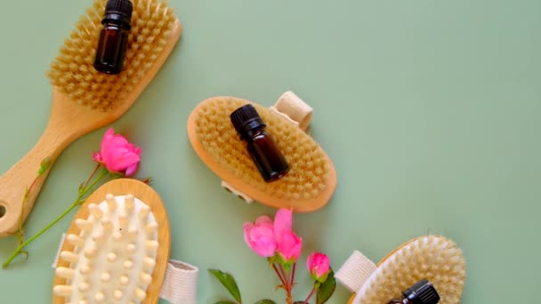 Olio di rosa. Spa, massaggi e aromaterapia. Set di spazzole per massaggi, olio in bottiglie di vetro e fiori di rosa rosa su fondo verde.Olio bio essenziale biologico — Video Stock