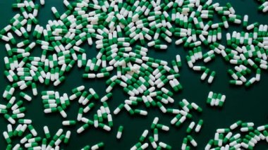 Yeşil arka planda homeopatik yeşil kapsüller. Tıp ve homeopati konsepti. Alternatif tıp. Yazmak için kullanılacak yeşil haplar. Kadın eli yeşil arka plandaki hapları kaldırır.