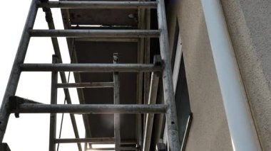 İskeleye yakın çekim ve güneş parlıyor. Ev inşaatı ve yenileme konsepti. İskeledeki evin temel ve duvarları. 4k görüntü