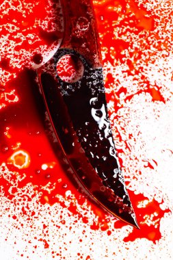 Keskin bıçak kan izleri ve sıçramalarla kaplı. Bıçağın üzerine kan damlaları düşüyor. Suç mahalli ve cinayet kavramı..