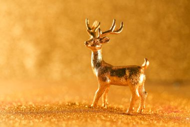 Yeni yıl ve Noel arkaplanı pırıl pırıl altın ışık ve yakın plan geyik figürlü altın renkli geyik heykelciğiyle parıldayan bir arka plan üzerinde altın bokeh ile çevrili. Altın tonlarda Noel duvar kağıdı.. 