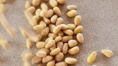 Soyulmuş çam fıstığı. Çam fıstığı çekirdeklerinin yakın çekimi seramik bir tabağa düşer. Sağlıklı beslenme yağları