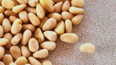 Fındık ve tohumlar. Çam fıstığı çekirdekleri seramik tabağa düşer. Keto diyet malzemesi. Fındık ve tohum. Faydalı sağlıklı atıştırmalık.