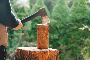 Isıtma mevsimi. Güneşli havada odun kesen bir adam. Balta ile odunları kıran bir adam. Isınma mevsimi için odun hazırlıyor. 
