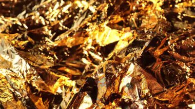 Altın folyo yaldızlı arka plan. Altın tonlarda desenli güzel bir arka plan. Folyonun metalik dokusunda yanar döner ışık. 4k görüntü