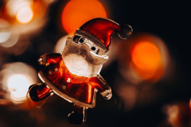 Noel Baba ve kırmızı bokeh siyah arka planda. Noel ve Yeni Yıl duvar kâğıdı. Parlayan Noel Baba heykelciği olan bir Noel arkaplanı. Bayram sembolü. Ilık, hafif bir Noel çelengi. Samimi