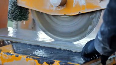 Döşeme kesimi. Siyah bir takım elbiseli bir adam güverte fayanslarını keser. Mekanik fayans kesme makinesi çalışıyor. 4k görüntü