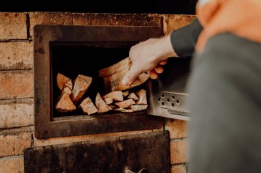 Ocakla ısıtılıyor. Brick Oven 'a odun yerleştiriyorum. Erkekler odunları ocağa istifliyor. Isıtma mevsimi. Adam Brick Oven 'a odun ekliyor..
