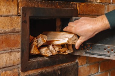 Sobayı ısıtıyorum. Ocakla ısıtılıyor. Brick Oven 'a odun yerleştiriyorum. Erkekler odunları ocağa istifliyor. Isıtma mevsimi. Adam Brick Oven 'a odun ekliyor..