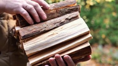 Bahçedeki bir adamın elinde odun parçası. Bir evi odunla ısıtıyor. 4k görüntü