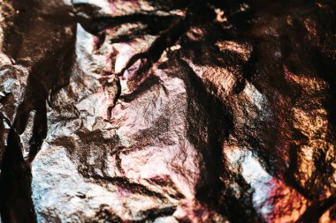 Renkli yansımalı folyo. Işıldayan folyo arka planı. Çok renkli folyoların katları ve katları. Yapılandırılmış Soyut Kırışık Folyo. Parlak, renkli bir maket. Boşluğu kopyala