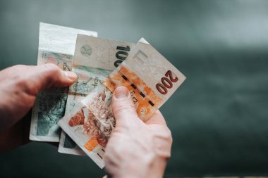 Tarafsız bir arkaplanda Çek Koruna banknotunu tutan eller. Para ekonomisi kavramı, mali farkındalık, enflasyon ve para yönetimindeki kişisel sorumluluk.