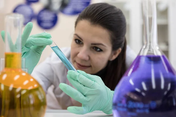 A female chemist examines the contents in a test tube. Work in a modern scientific laboratory.