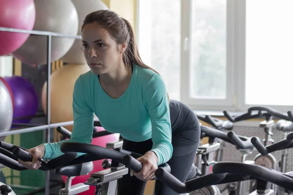 Athletic woman on an exercise bike in the gym. A young woman does exercises to lose weight and maintain physical fitness. Movement is life. The concept of an active lifestyle.