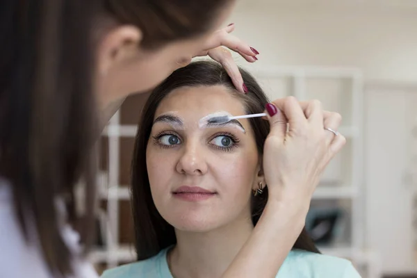 The master applies a special shampoo to the client\'s eyebrows to clean them before painting with paint/henna. The process of cleansing the skin in the area of the eyebrows and the eyebrows themselves.