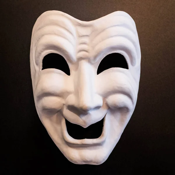 White theatrical mask on a black background. The mask of comedy. Venetian carnival masks.
