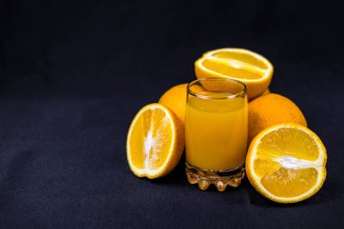 Siyah arka planda dilimlenmiş portakallı taze sıkılmış bir bardak portakal suyu. Uzayı kopyala Uygun beslenme ve çevre dostu ürünler kavramı.