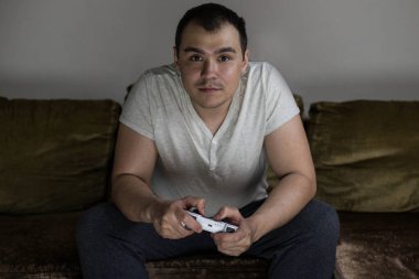 Akşamları evde bir adam kanepede oturup konsolda oyun oynuyor. Esporlar. Oyun konsolları.