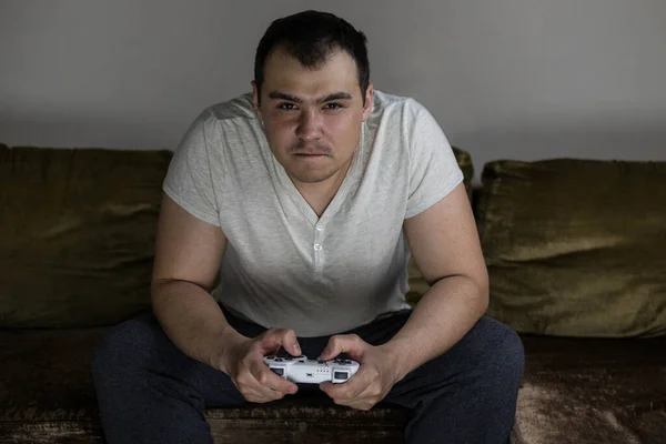 A man plays a video game console and is angry that he is losing. A disgruntled man loses in a video game.