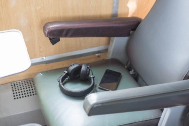 Uzun bir yolculukta akıllı telefonunuzla kulaklıkla müzik dinleyin. Tren koltuğunda kulaklık ve telefon var. Tren yolculuğundaki eğlence.