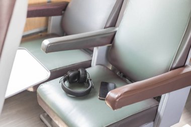 Tren koltuğunda telefon olan kulaklıklar. Modern şehir yaşam tarzı ve konforlu seyahat kavramı. Kulaklıkla müzik dinlerken iyi yolculuklar..