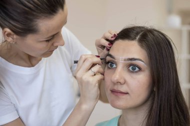 Kaşları şekillendirmek için kaşlar arasında yardımcı çizgiler oluşturun. Kaşların mikro pateni. Kına ya da boyayla kaş boyama. Kalıcı makyaj.