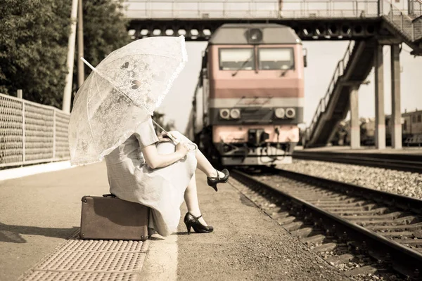 Młoda Kobieta Białym Parasolem Siedzi Walizce Tle Pociągu Wjeżdżającego Peron — Zdjęcie stockowe