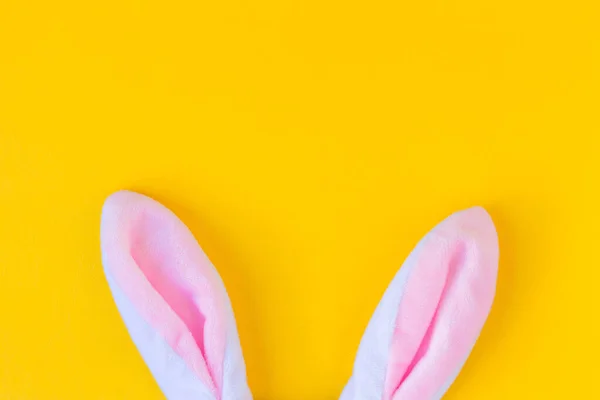 Sarı arka planda peluş tavşan kulakları. Minimalist Mutlu Paskalyalar konsepti. Tasarım için boş alan.