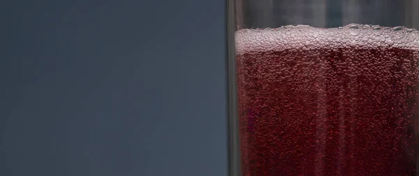 red soda water splashing with bubbles close up and Dew Point on glass