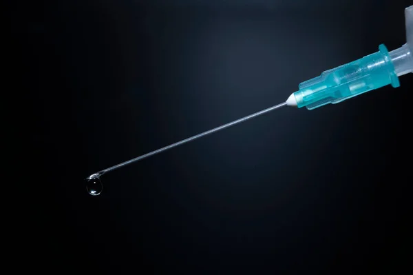 Kanüllü bir şırıngayı yakın çekim yap ve koyu mavi arkaplanın önüne bırak.