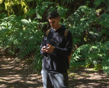 Yeşil ormanda cep telefonunu kullanan bir adam.