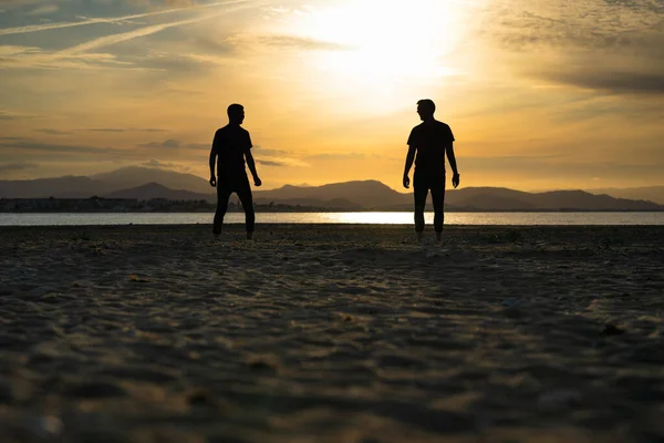 Two Silhouettes Men Beach Looking Each Other Sunset Sea Mountains — Stock Photo, Image