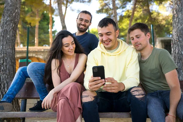 Bir grup arkadaş gülümsüyor ve cep telefonlarına bakıyor..