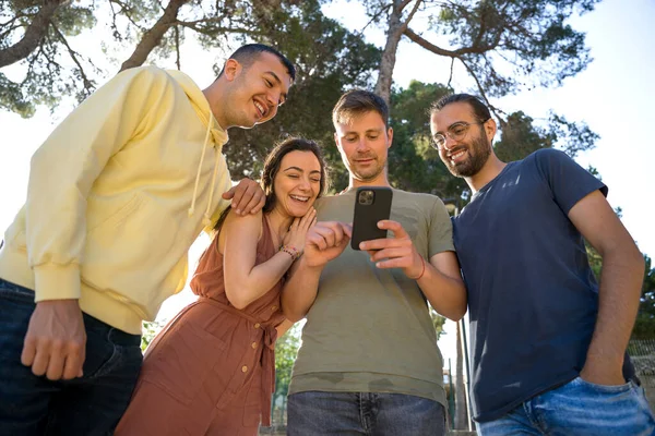 Arkadaşlar cep telefonuna bakarken gülümsüyor
