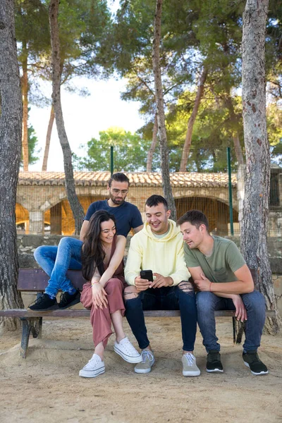 Bir grup arkadaş gülüyor ve cep telefonlarına bakıyor..