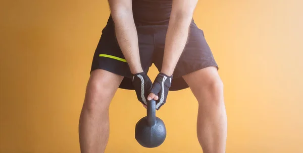 Kettlebell ile egzersiz yapan tanınmayan bir adamın resmi.