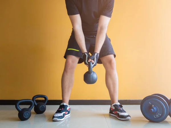 Kettlebell ile egzersiz yapan tanınmayan bir adamın resmi.