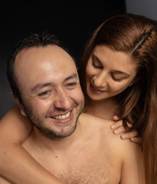 Kız arkadaşı ona sarılırken gülümseyen adamın stok fotoğrafı.