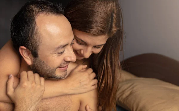 Yatak odasında gülümseyen ve konuşan bir çiftin stok fotoğrafı.