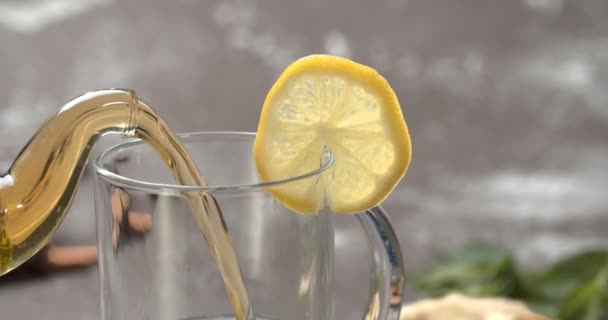 Sárga citromos tea teáskancsóból mentás pohárba, lassított felvétel, közelről — Stock videók