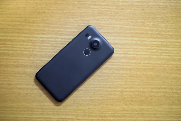 Ahşap masa üzerinde siyah akıllı telefon Üstten Görünüm